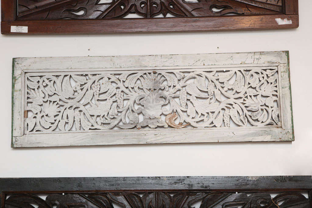 A white painted wall panel or screen with carved floral and bird motif.