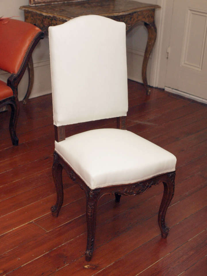 A set of 8, very sturdy, dining chairs with upholstered seats and backs, the backs arched, and the seat rails bowed; on cabriole legs and the legs and seat rails finely carved.