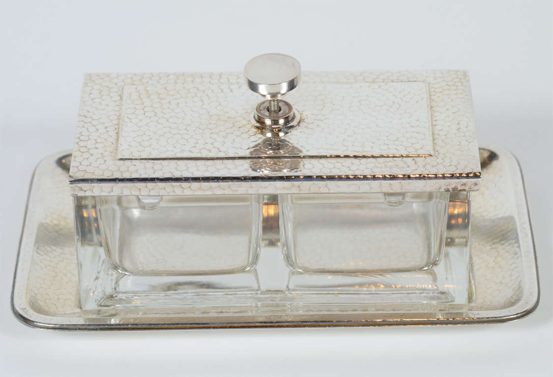 This beautiful condiment holder features a sliding top and base in a silver-plate snakeskin design. It is fitted with a two compartment  holders for condiments with a lip for a serving piece like a spoon. It is signed on the base Alpacca