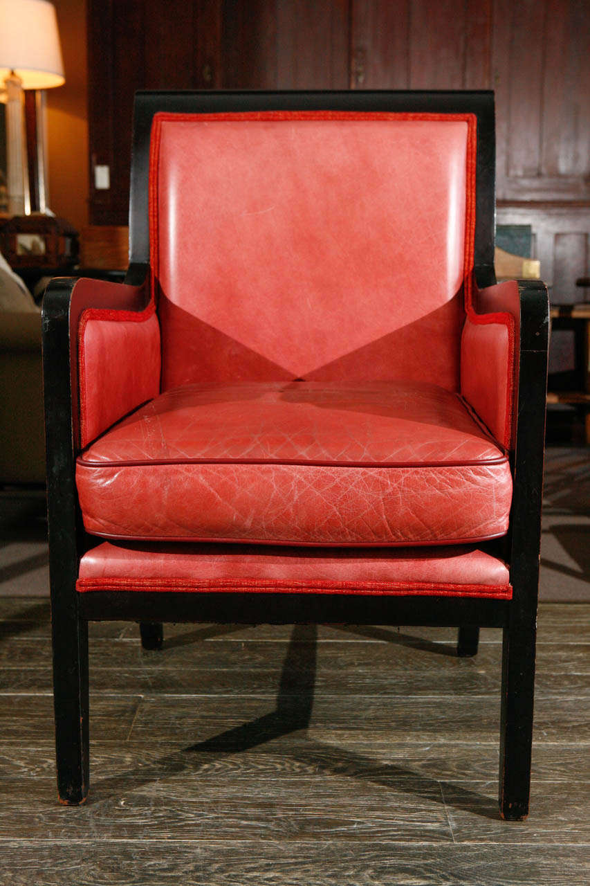 A pair of ebonized armchairs in red leather.