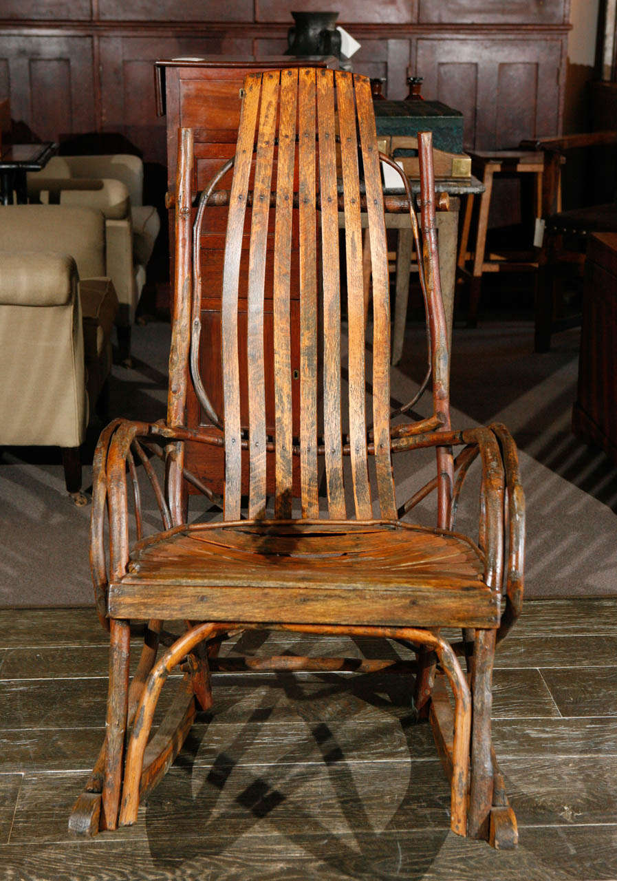 A rustic oak slat rocker with unique curled and shaped branch design.