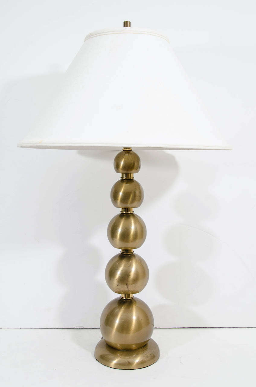 A vintage pair of brushed brass stacked ball table lamps with shades.  Some pitting and scratching to the brass.