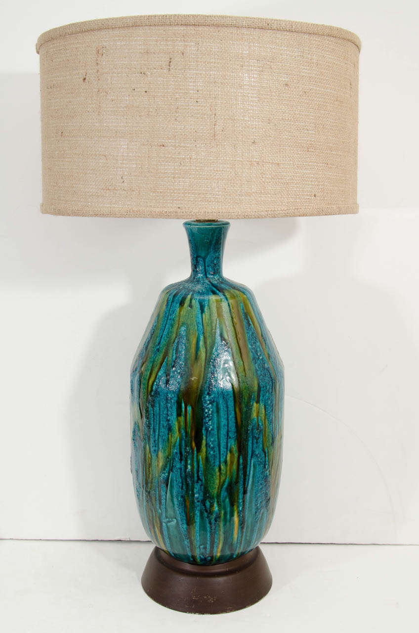 A vintage blue and green ceramic table lamp with burlap shade and wood base.