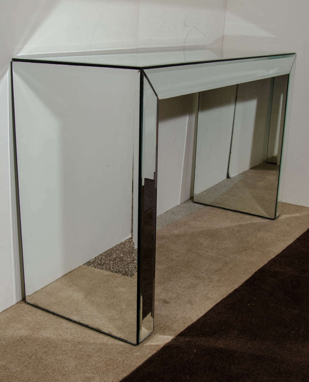 A vintage console table, desk or vanity with mirrored surfaces. The piece is finished on all sides. Good vintage condition with age appropriate wear; the piece has a longer scratch on the surface as well as scratches throughout which are