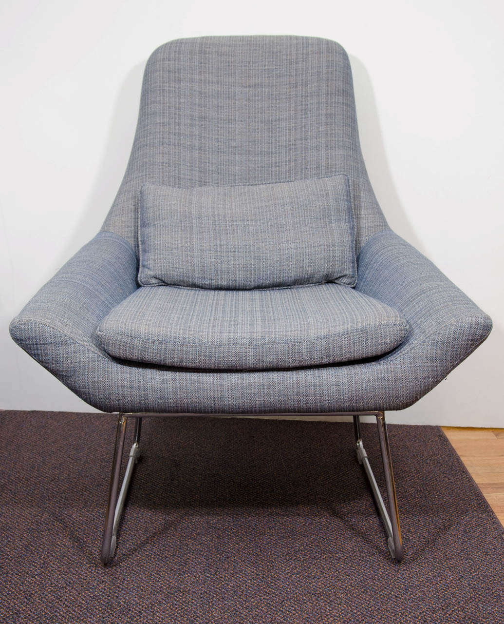 A vintage lounge chair with chrome base and newly upholstered in a blue twill.