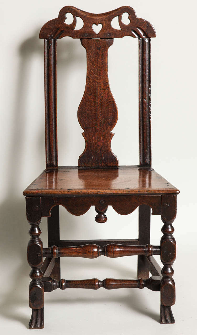 Charming and quirky Welsh oak folk art side chair, the arched crest with pierced hearts and moons, over balustrade silhouette back splat, the two stiles with molded decoration, over  thumb molded plank seat over scalloped rail having drop finial,
