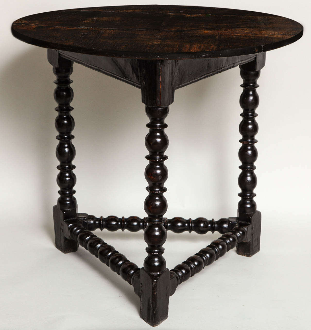 Rare Charles II oak cricket table, the vividly and densely grained top over triangular base having molded apron joining egg and reel turned legs joined by similarly turned stretchers, the whole possessing a beautifully rich patina.