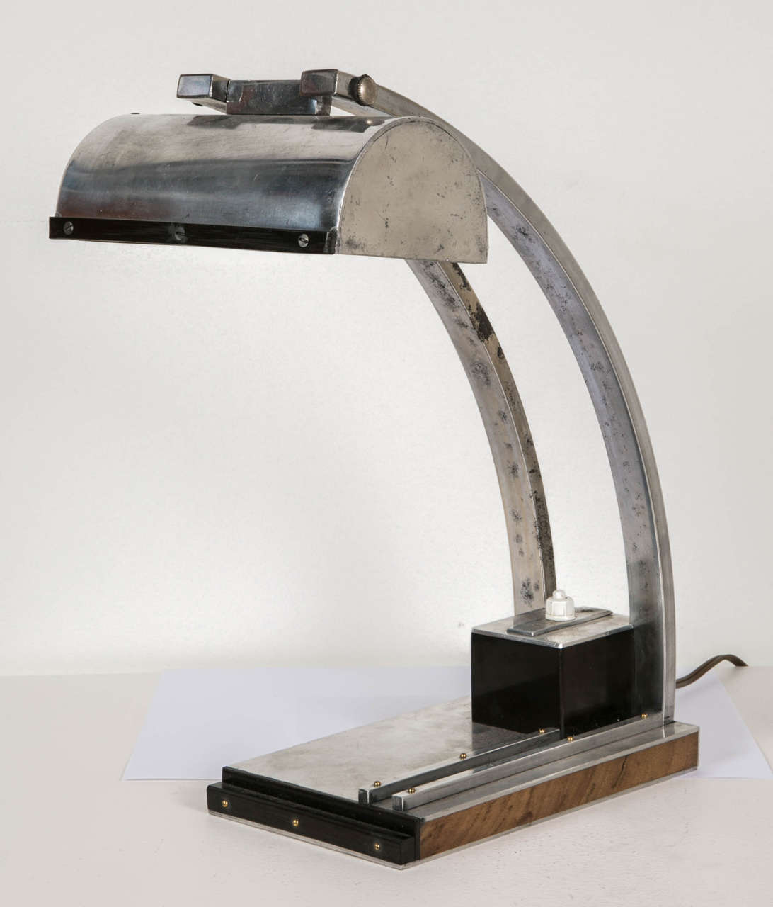 Modernist desk lamp in chrome metal, hard rubber and natural wood architected base supporting a semi-cylindrical lampshade. French work of the 1930s in the spirit of Jacques Le Chevallier and René Koechlin.
European standard wiring.
