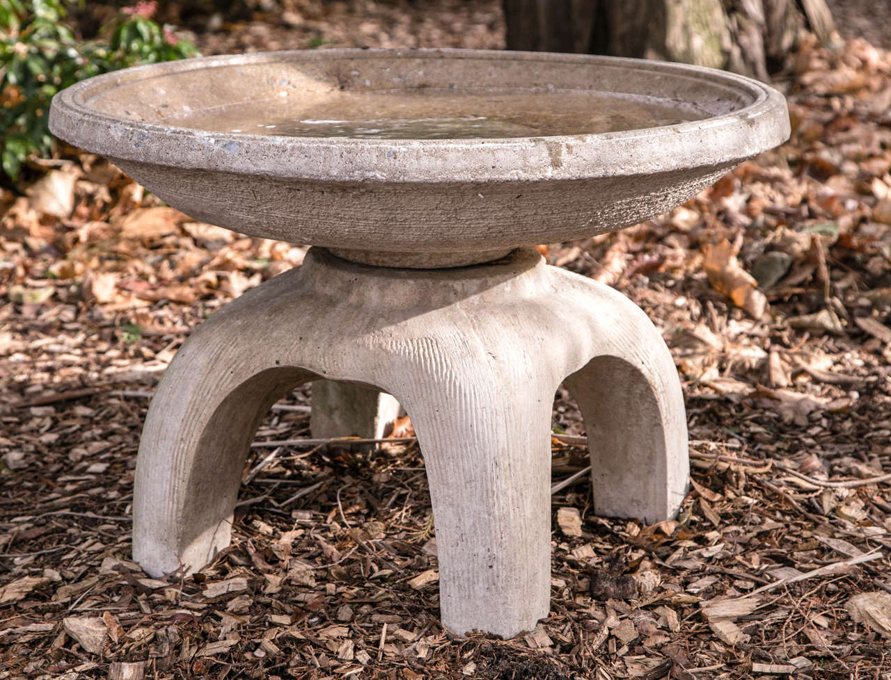 A composition stone birdbath in the Japanese style, comprised of a simple wide bowl on four-legged base.