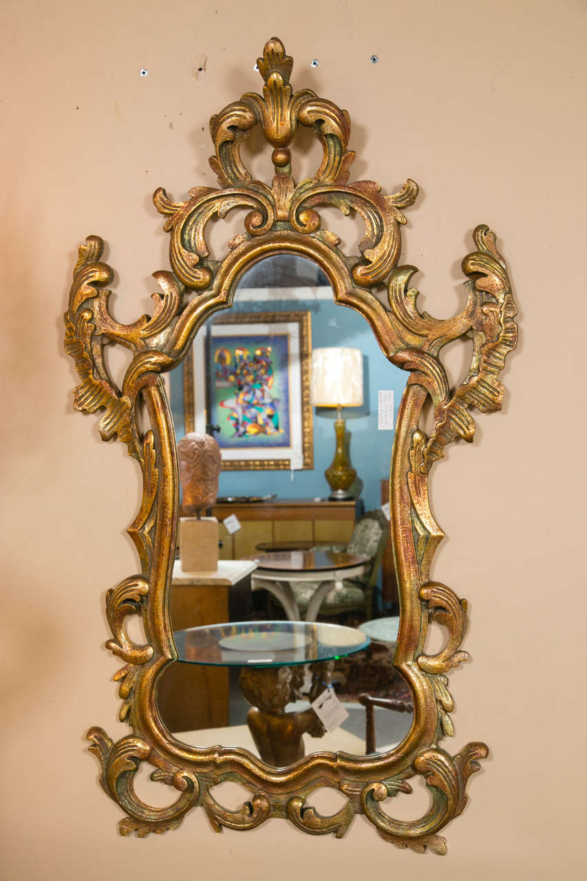 Pair of gilt Rococo carved mirrors. The Louis XV style mirrors having a fine parcel-gilt and undertone paint decorated finish. The center mirror panel is framed in a scroll and vine design with some leaf highlights. This wonderful pair of wall
