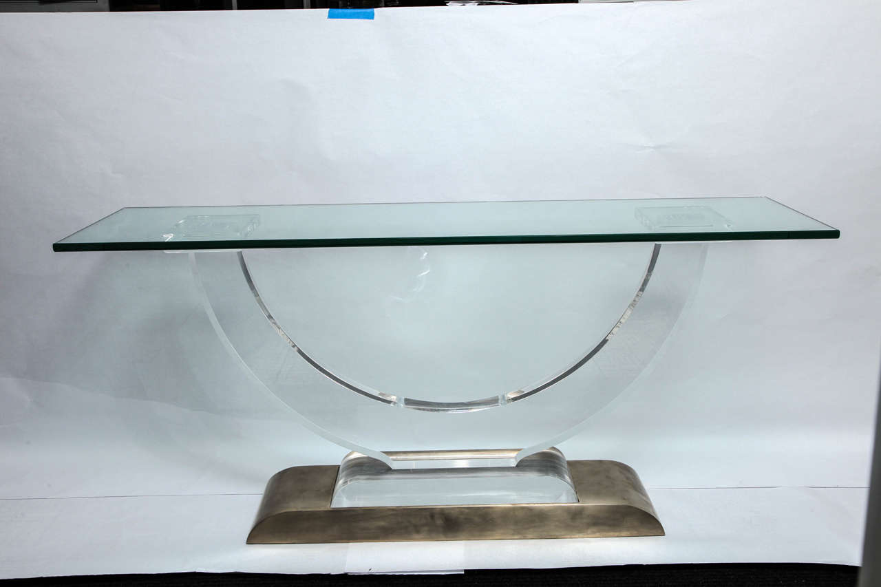 A 1970s architectural console table, influenced by the style of designer Karl Springer, crafted of U-form lucite and heavy base in polished bronze.