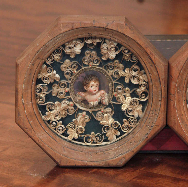 Pair of Shadow boxes with 19th c. polychromed putto heads surrounded with rolled paper decoration in fruitwood frames.