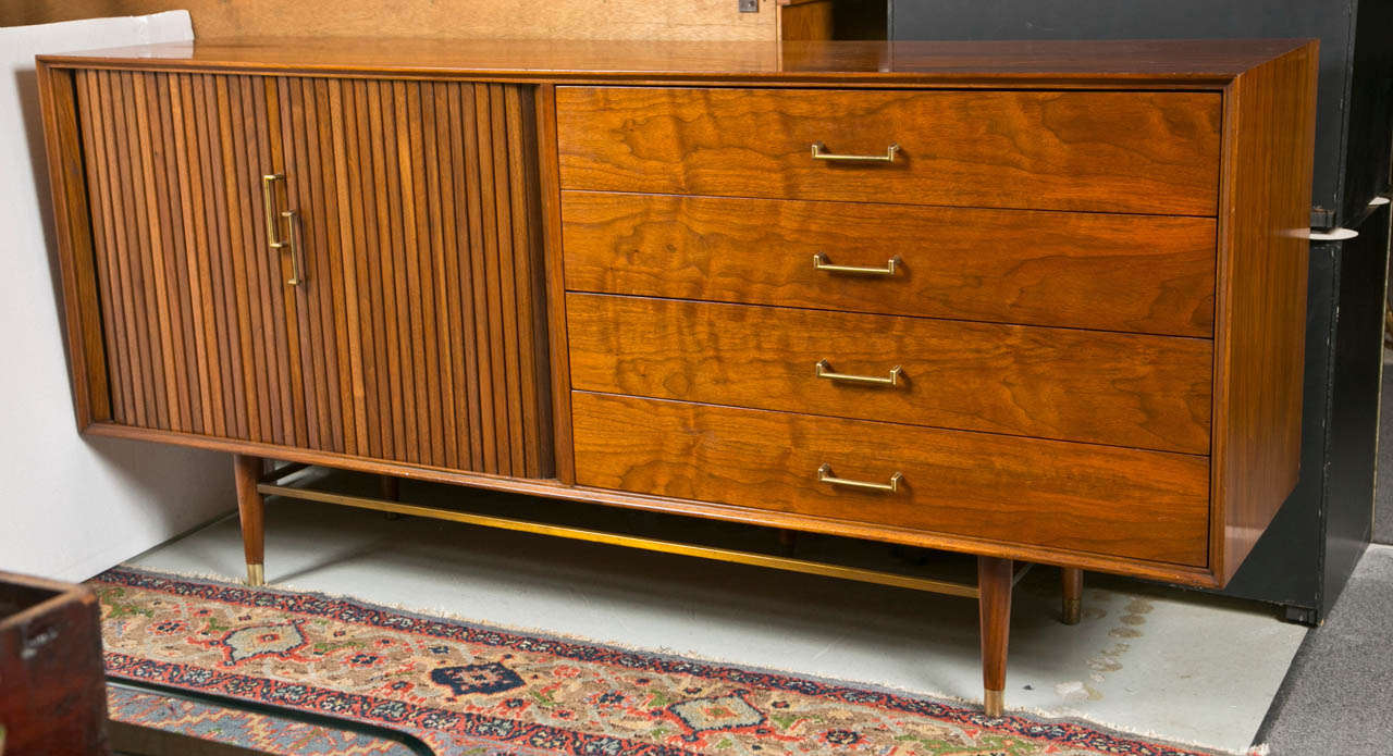 Mid Century Modern Danish Rosewood dresser, the low and oblong case fitted with a pair of tambour doors opening to three drawers, and a set of four drawers decorated with brass pulls. Raised on tapering legs joint by brass stretcher. Custom Quality.