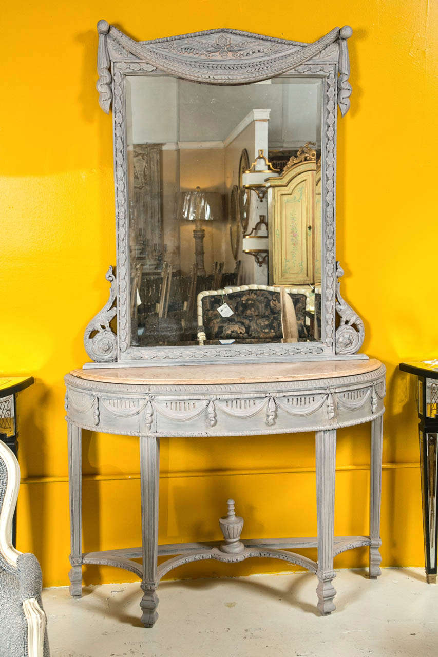 A beautiful French, Louis XVI style grey polychromed vanity, the set includes a mirror and a marble top console, the mirror with an elegant drapery motif on the top and scrolled details on each lower side, raised on a marble top half-moon console