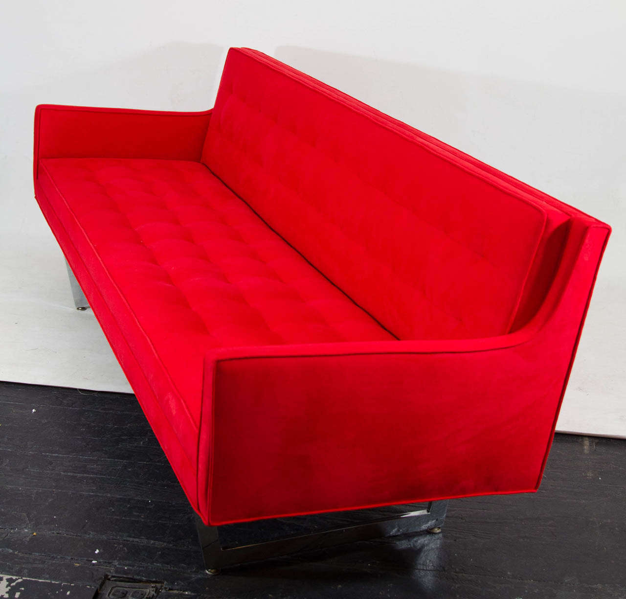 Gorgeous and sleek Patrician sofa! The sofa has great lines and profile and floats on angled chrome supports. The sofa is upholstered in a bold red ultra suede and tailored with buttonless tufting. Please contact for location.