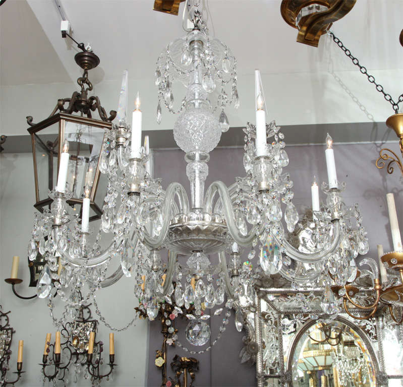 An eight light English George III style chandelier with crystal arms issuing from scalloped edge dish with crystal the center shaft covered with orb and vase shaped elements, the umbrella shaped upper element draped with crystal drops . Chandelier