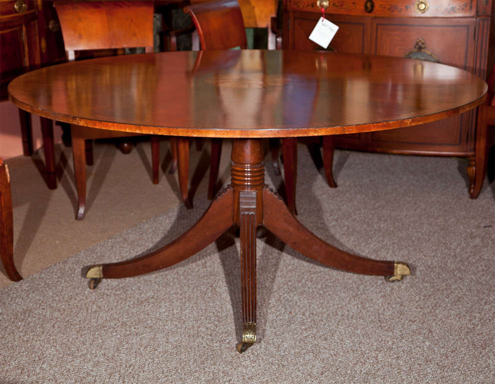 English Regency style mahogany custom quality banded and sunburst inlaid circular dining centre table, raised on a single pedestal supported by quadrupple legs ending in brass caps and casters.