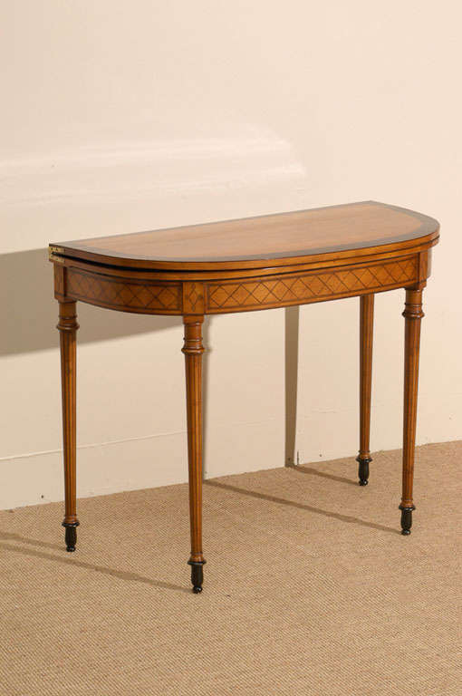 A fine English George III satinwood card table, attributed to Henry Holland, London, circa 1800. The top is decorated with a wide mahogany band surrounding the rich satinwood center. The frieze has a repeating geometric line inlay and the legs with