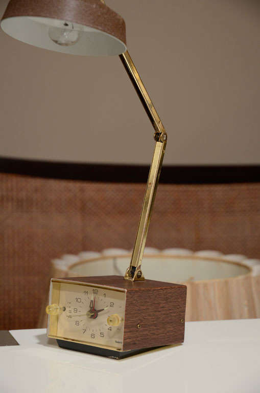 Task lamp with combination clock and alarm by Tensor.  USA, circa 1950.  Fully functioning clock and alarm.  <br />
<br />
Features a brown metal shade, faux wood grain base and brass accents.  Fully adjustable arm.<br />
<br />
Item may be viewed