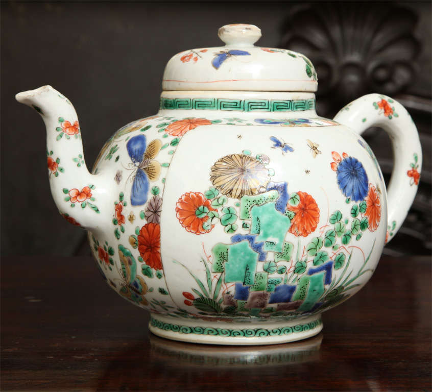 Antique Chinese porcelain punch pot, the body of compressed globular form with tall out-curved spout, heavily potted loop handle and boldly domed cover with stud finial, finely decoratedin famille verte enamels with panels of flowering plants