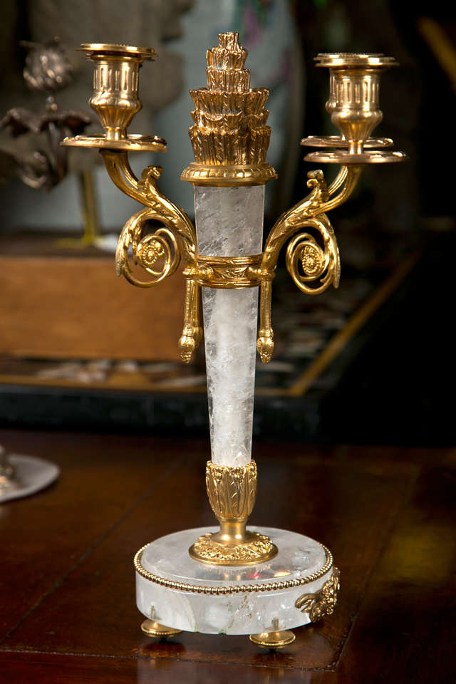 a pair of gilt bronze and rock crystal  4 light candelabra  in the louis  xvi style. the circular base with gilt  bronze disc feet, tapered central column with  typical louis  xvi style gathered arrow feathers at top,  and  acanthus leaf bottom.