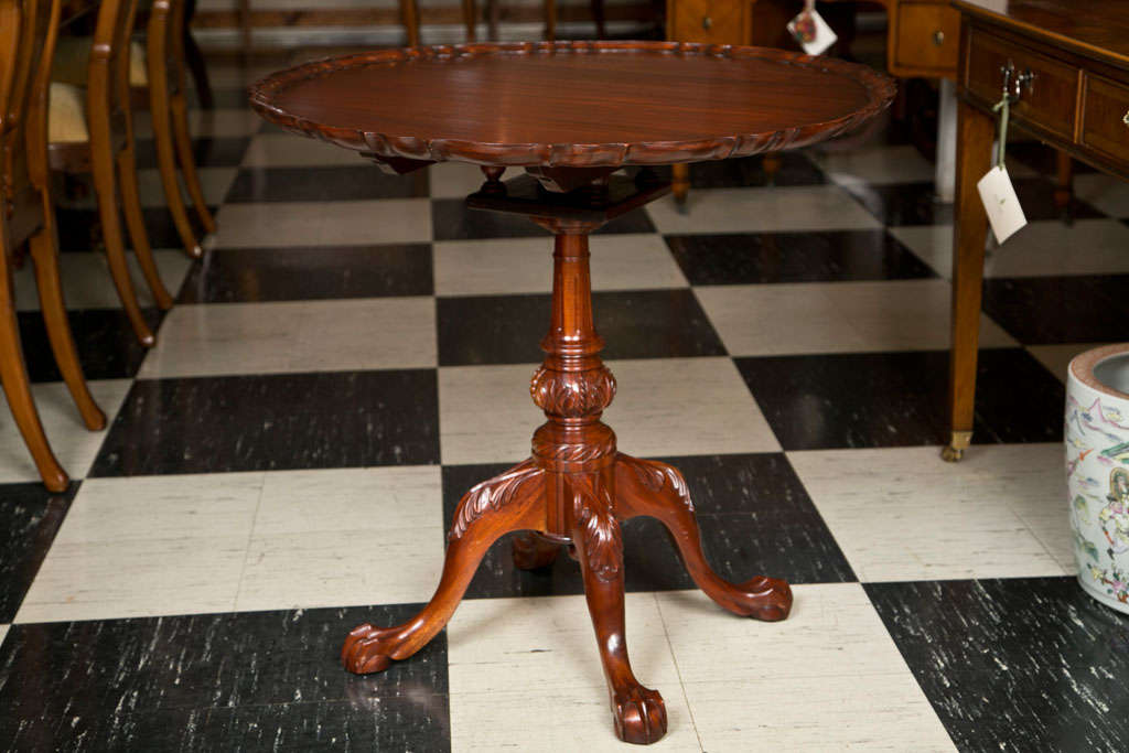 Made for us in England, this Classic tilt-top tea table on a four leg base features a pie crust edge and acanthus leaf carving on the legs that terminate in well-executed claw and ball feet.
