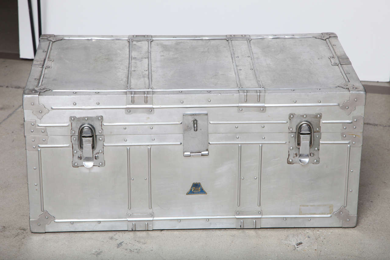 Pre-world war II.  Lift-top aluminum trunk with lots of structural detail.  Single lift-out tray and paper-lined interior.  Makes terrific coffee table/side table.
Original condition.