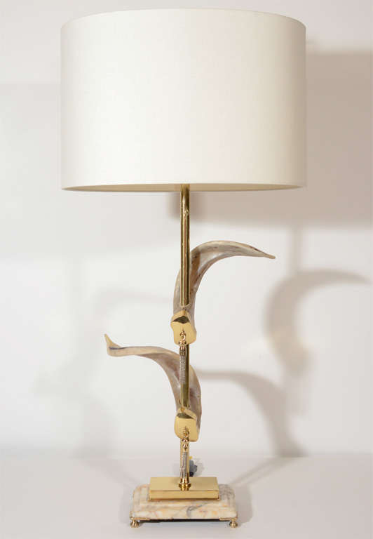 Pair of outstanding brass table lamps with genuine rams' horns design. The lamps have beautiful stepped exotic marble bases which have been hand polished. The lamps also have stylized brass fittings with brass tassels. Shown with custom linen oval