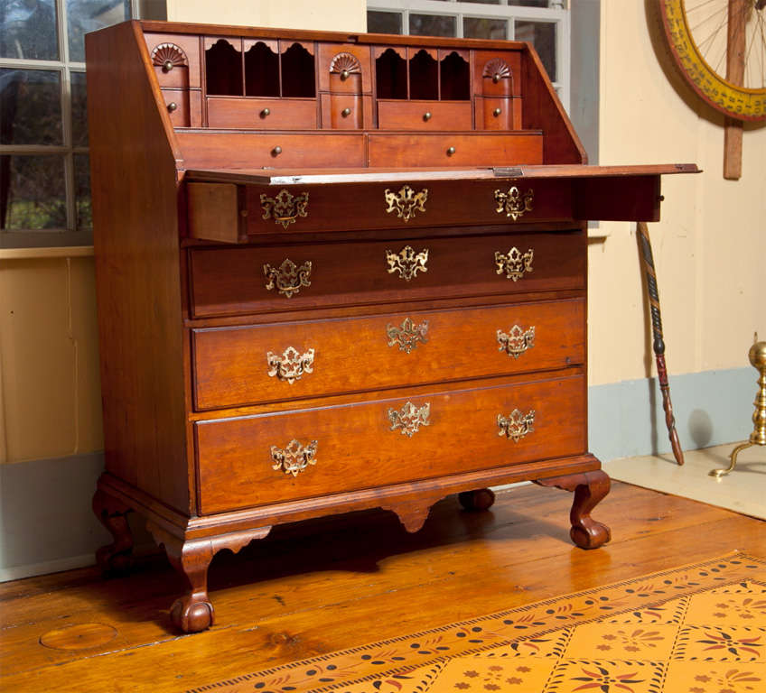 A Connecticut Slant-front desk with four ball and claw feet, a triple block and shell carved interior with six pigeonhole valances and a stepped lower level.  The embellishment of the center drop and four ball and claw feet distinguishes this desk