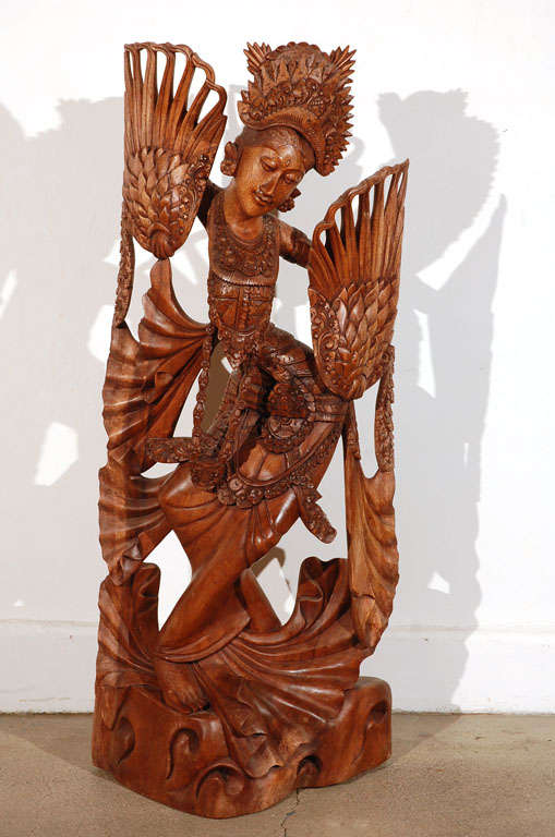 Intricate solid mahogany wood carving of a Balinese Barong Dancer Goddess. The woman is depicted performing a traditional Balinese dance, elegant, peacefull face, a lot of details.