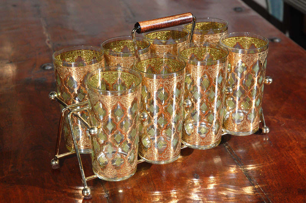 Elegant Vintage bar ware glasses with Valencia pattern in<br />
a gold leaf finish. Set includes 8 highball glasses in a brass cart with a wood handle.<br />
Vintage glasses from Culver with 22 Karat Gold encrusted and green Diamond Shapes