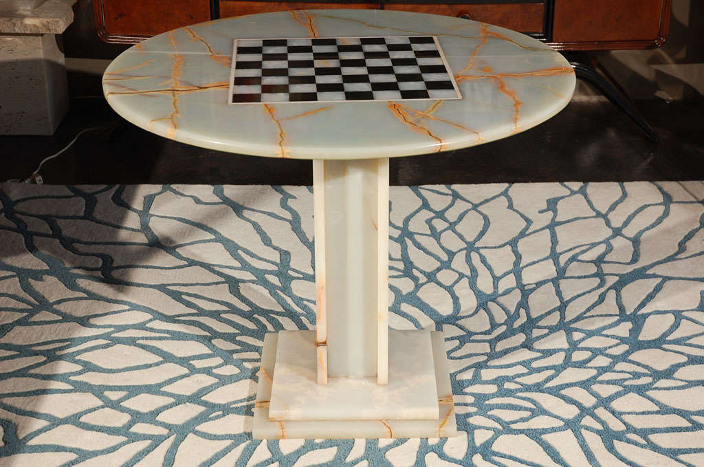 A stunning solid onyx game table with an inlaid chess/checker board in the center. Note the gorgeous detailing of the of the veins. Onyx top is supported by a wood bottom.