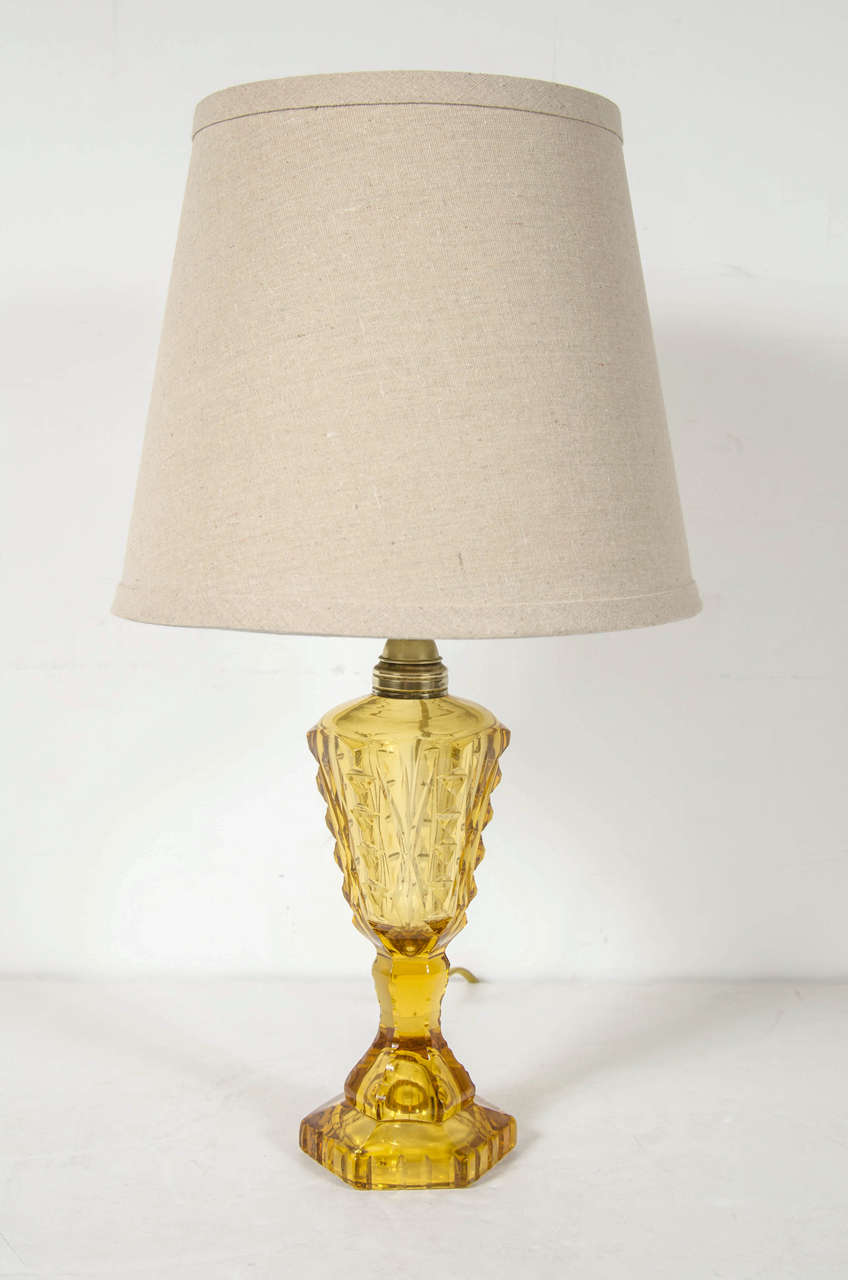 This elegant table lamp was realized in the United States, circa 1935. It features an exquisitely cut balustrade form with stylized Art Deco detailing and has brass fittings in a rich translucent amber hue. With its refined palate and clean