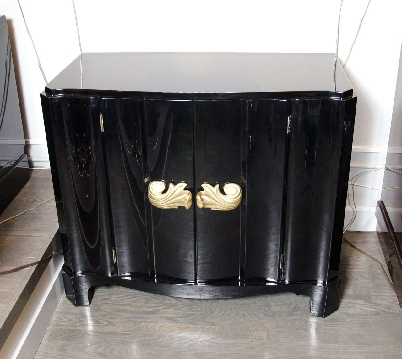 This exceptional 1940s Hollywood serpentine cabinet by Dorothy Draper consists of ebonized mahogany with acanthus style brass pulls on paneled doors. It's depth provides ample storage and is raised slightly off the floor. This stunning piece is a