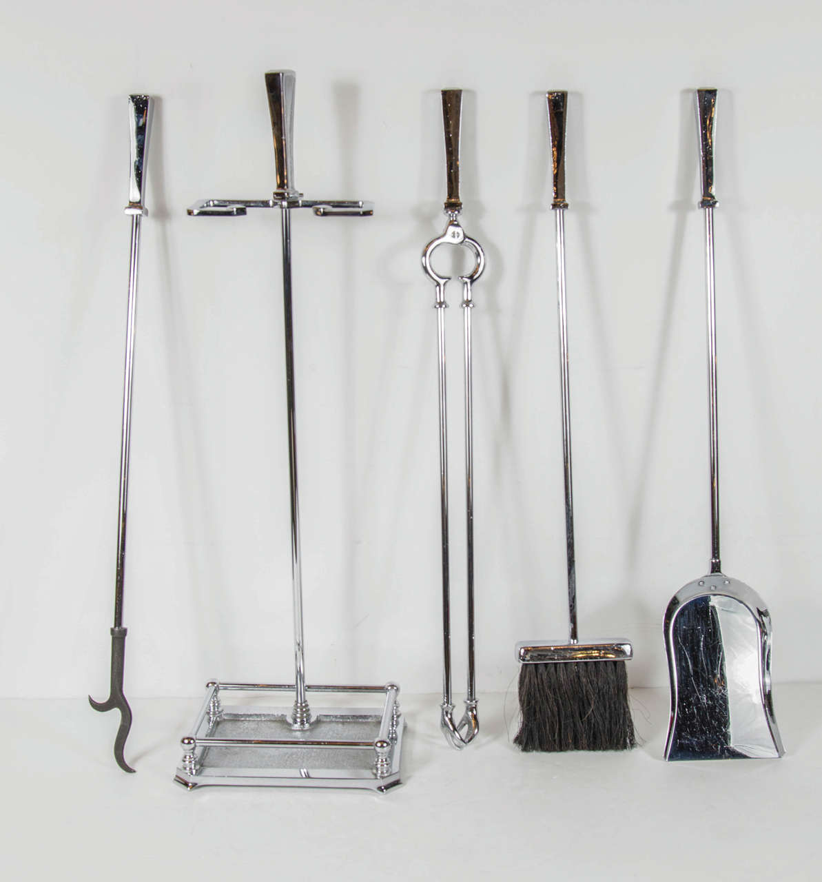 This very sophisticated Mid-Century Modernist Fire tool set features an all chrome design with elegant stylized, and tapered geometric handles. The set  includes a shovel, log holder, poker, brush and stand.