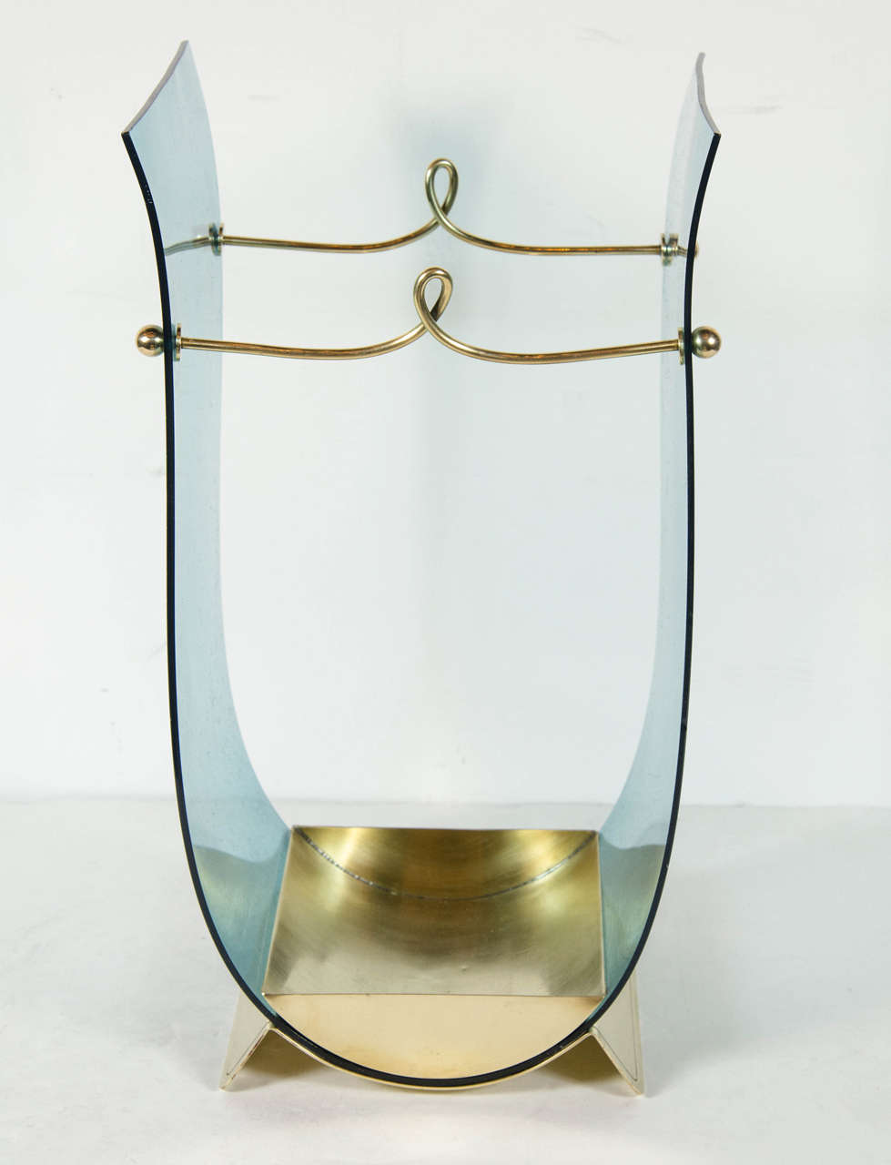 This gorgeous Mid-Century Modernist umbrella stand in the manner of Adnet features a pane of turquoise lucite suspended in a U-form by two sculptural brass fittings which also serve the purpose of containing umbrellas. It has a brass receptacle