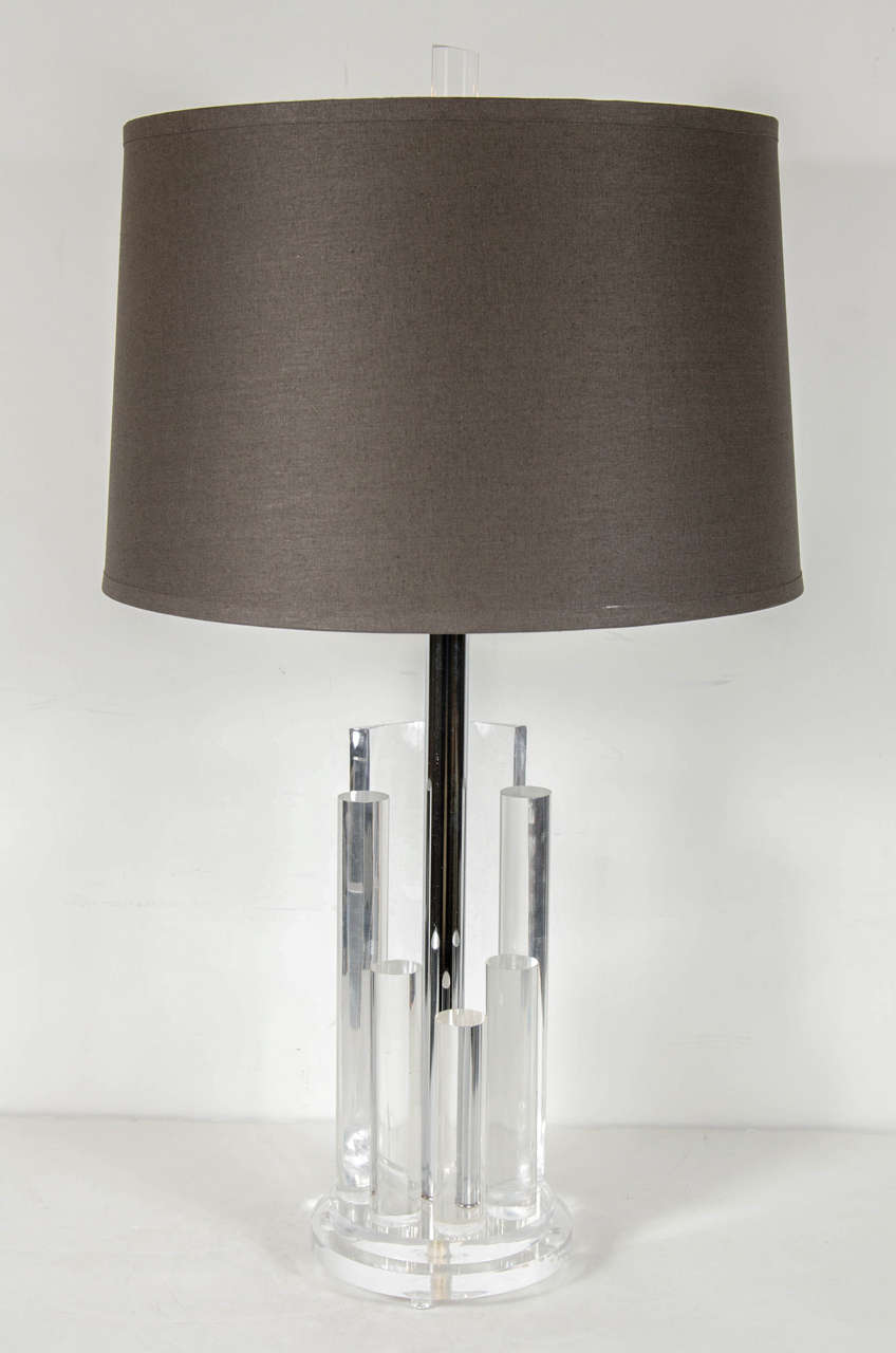 This sculptural pair of Mid-Century Modernist table lamps feature a skyscraper design with Lucite rods at varying heights and a Lucite arc surrounding a chrome stem on a round stepped Lucite base. Each lamp has two bulbs which can be operated