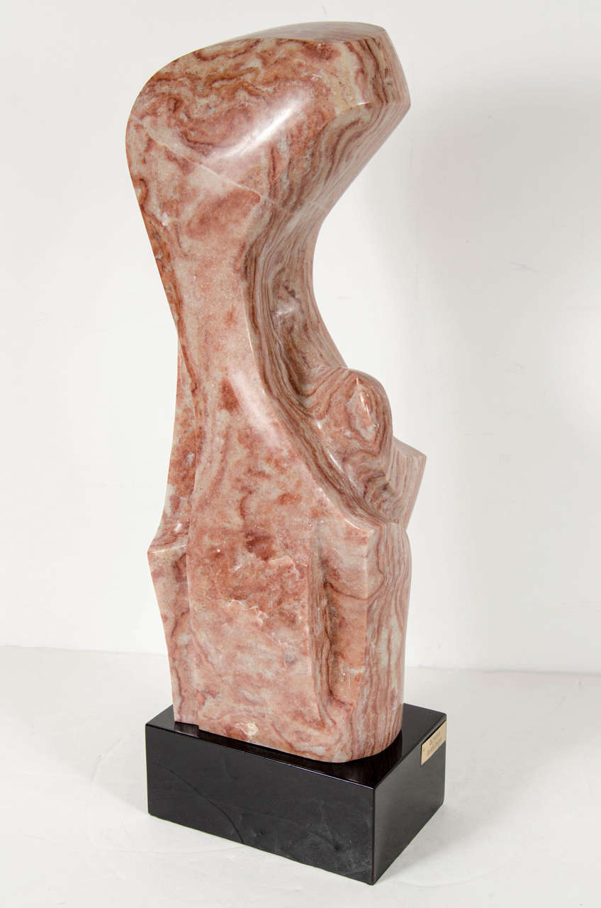 This hand-carved exotic marble sculpture features an organic free-form design which rests on an ebonized walnut pedestal with a plaque with the artists name Doris Gross hand engraved on it.