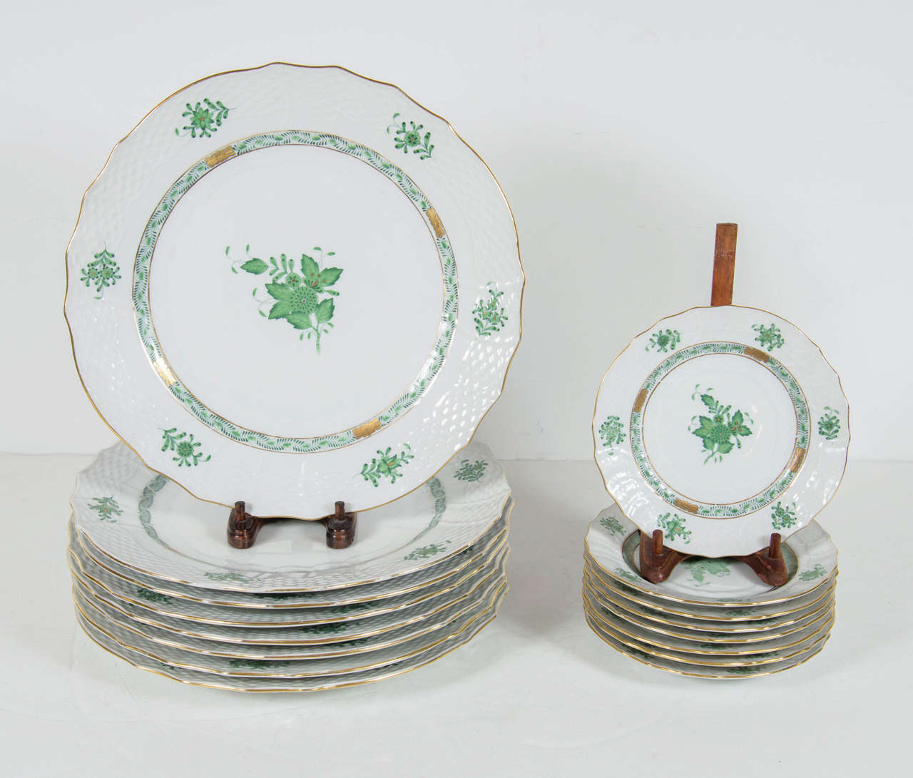 These sets of 8 platers feature a white glazed porcelain with green polychromed and gilt floral decoration by Herend.They are hand painted by the renown Hungarian firm Herend. They are adorned overall with delicate floral stems in a pale green. They