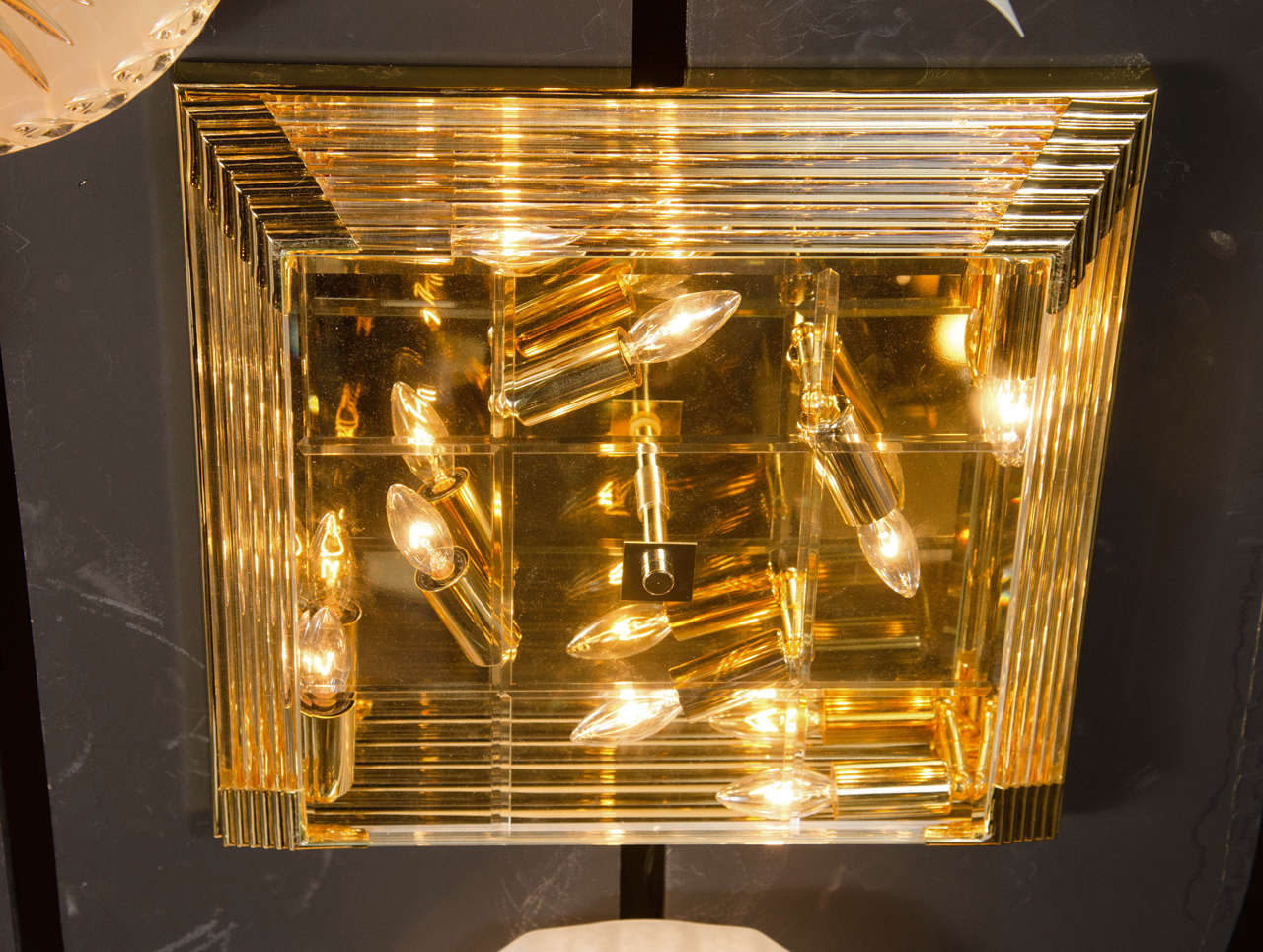 Mid-Century Modernist square brass and glass rod flush mount chandelier. This flush mount chandelier features a stepped designed square shape that is comprised of horizontally staggered glass rods that are stacked in a descending fashion leading to