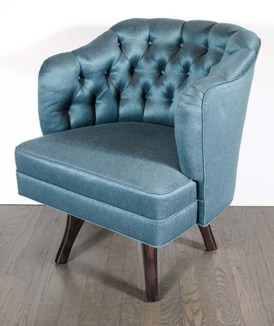 This gorgeous pair of Mid-Century Modernist swivel chairs consist of a fully upholstered seat with deep button detailing on the back, splayed taper legs in ebonized walnut and new teal sharkskin upholstery. Restored to mint condition.