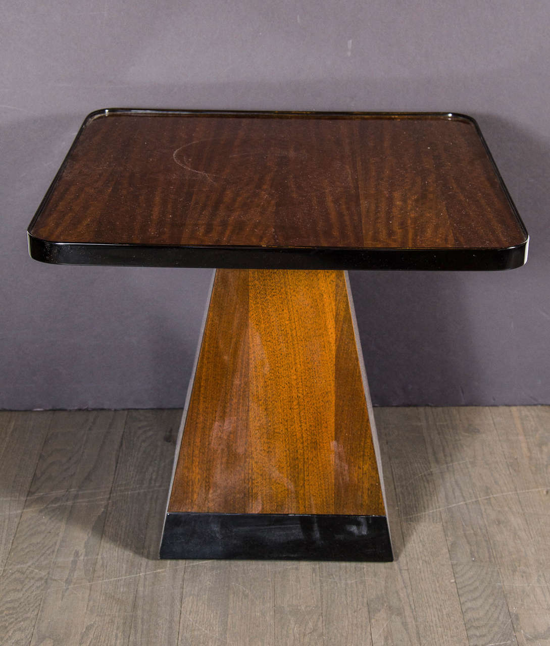 This superb Art Deco occasional table features strong geometric design banded in black lacquer around the edge of the square table top and the base which contrasts nicely with the warm tones of the book matched exotic mahogany. Restored to mint