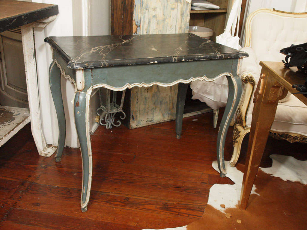 Beautiful painted french table in a beautiful hue of blue green with white details and black marbelized top.  Cabriole legs and carved details.  Single front drawer for storage on long side of table.