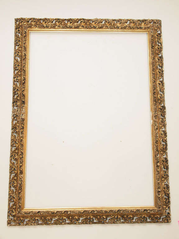 Large gesso and giltwood Rococo style frame intricately carved with a solid inner section and an openwork outer section; both carved with foliage, flowers, c-curves and s-curves.