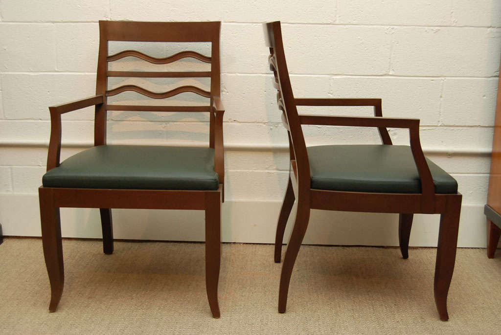 Here is a pair of elegant walnut arm chairs upholstered in a forest green leather.