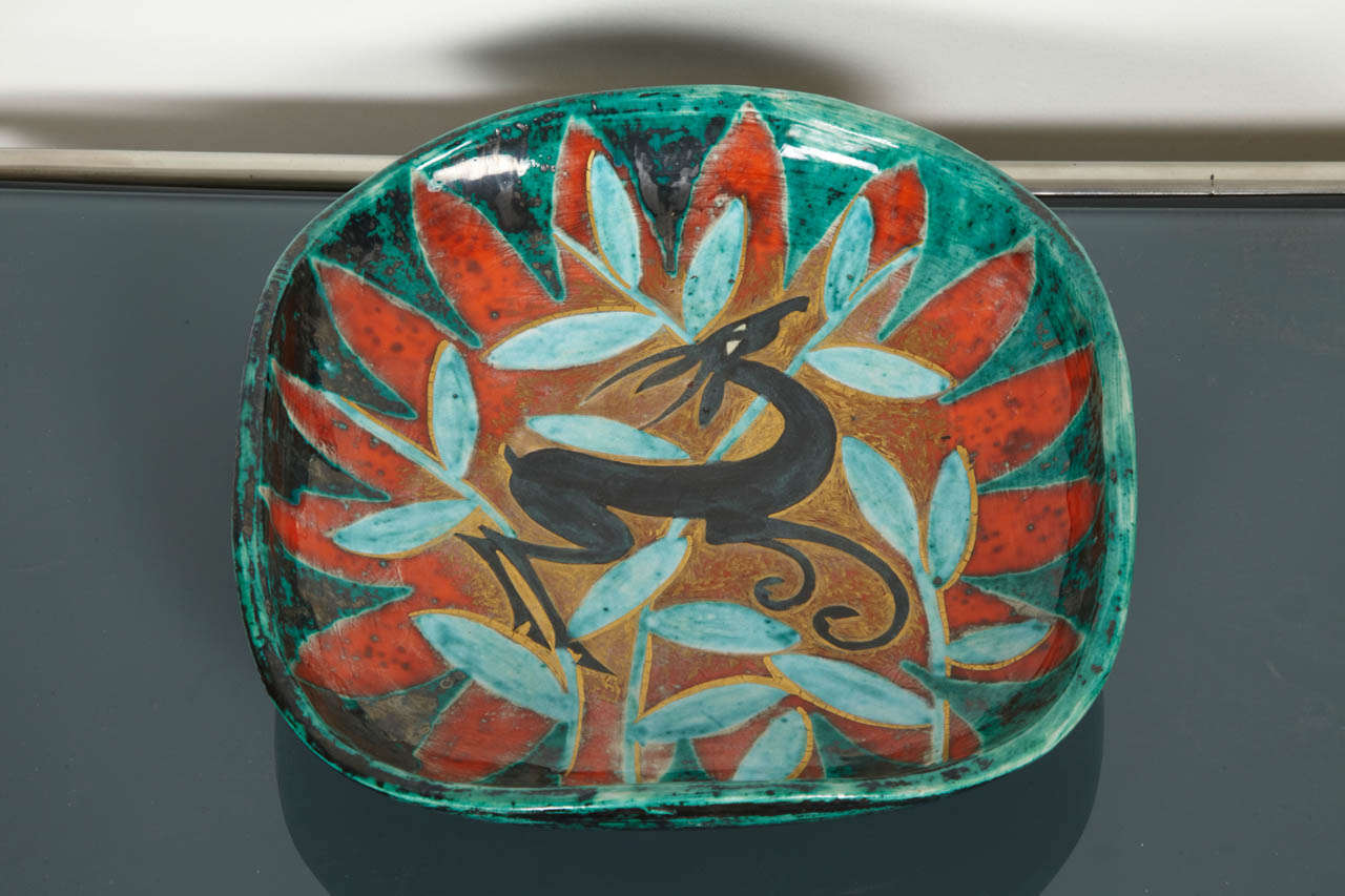 Enameled ceramic plate by Edouard Cazaux (1889-1974) representing a black cervid on a golden, red and green background and a leaf decor. Signed under the base.