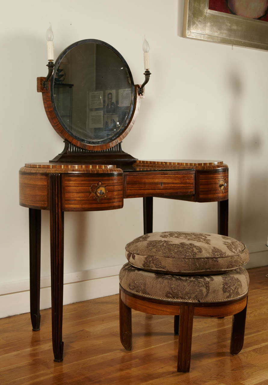 Mahogany dressing table with arrow-tip legs and wound motif feet. Three side drawers, two drawers decorated with floral adornment marquetry (made of mixed woods, metal and ivoirine). Silver plated circular mirror. Two small lighted bronze torcheres.