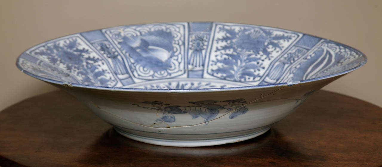 A massive Japanese Arita blue and white 'kraak'-style deep charger, late 17th century, decorated with a central medallion showing branches bearing fruits, within a border of alternating panels of flowers and leafs. Dishes with panelled borders were