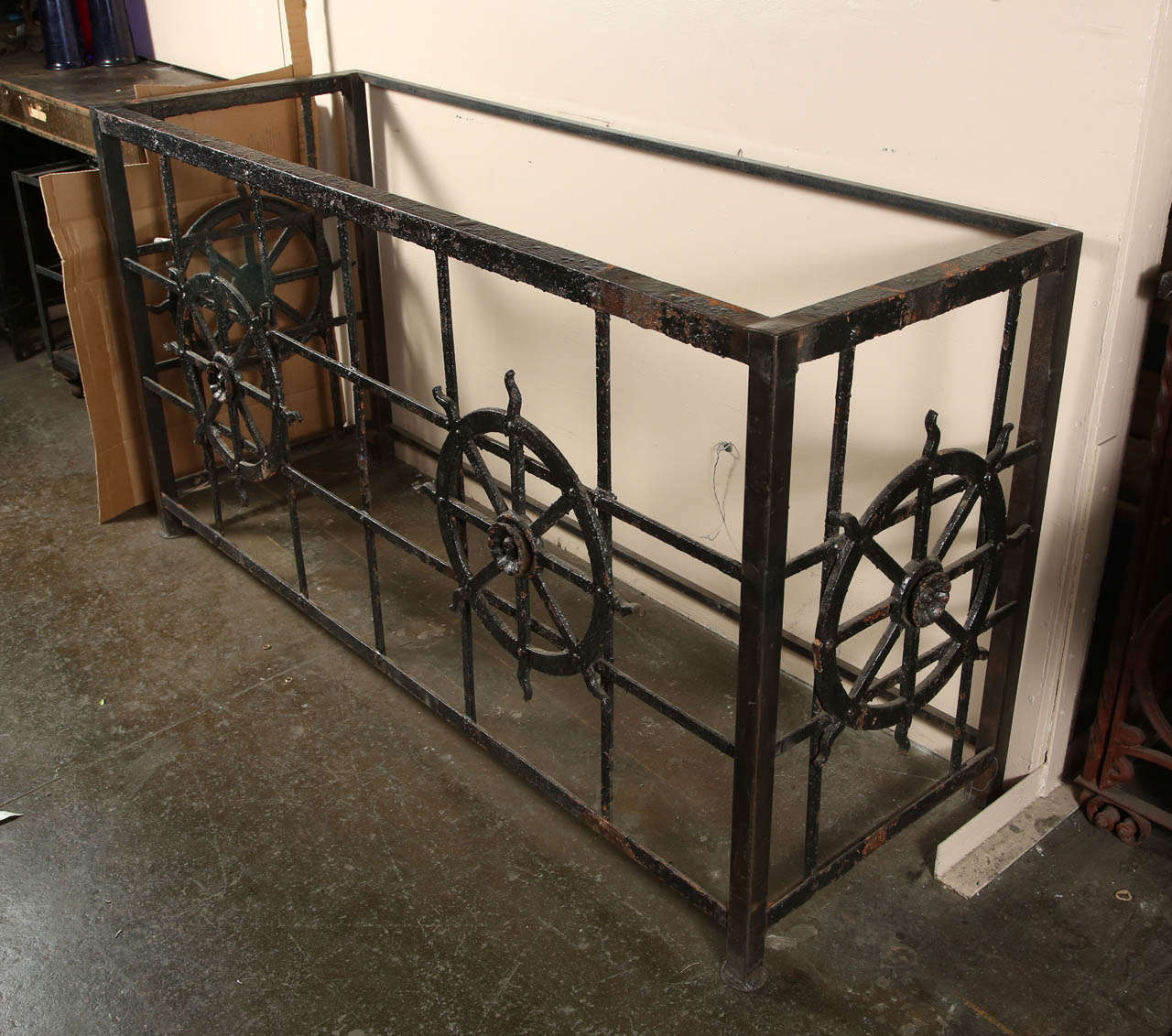 This is a cast iron black console table. Recently made from a salvaged balcony. It has cross hatch metal sides with cast iron ship wheels welded on to the sides. This can be seen at our 1800 South Grand Ave location in Downtown Los Angeles, CA.