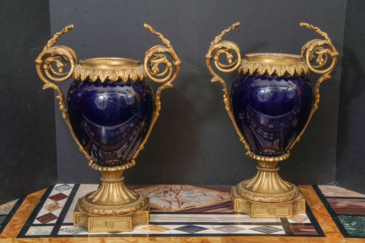 This large and exciting pair of vases in a deep cobalt blue glaze are french in manufacture. Made as decorative elements for a grand house in France in the third quarter of the 19th century. The body of the vase is designed to set within the gilded